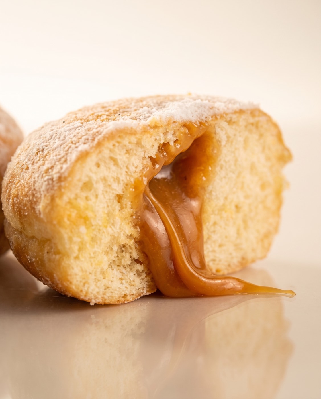 Studio Berliner on a cream background, with caramel oozing and a reflection on the surface